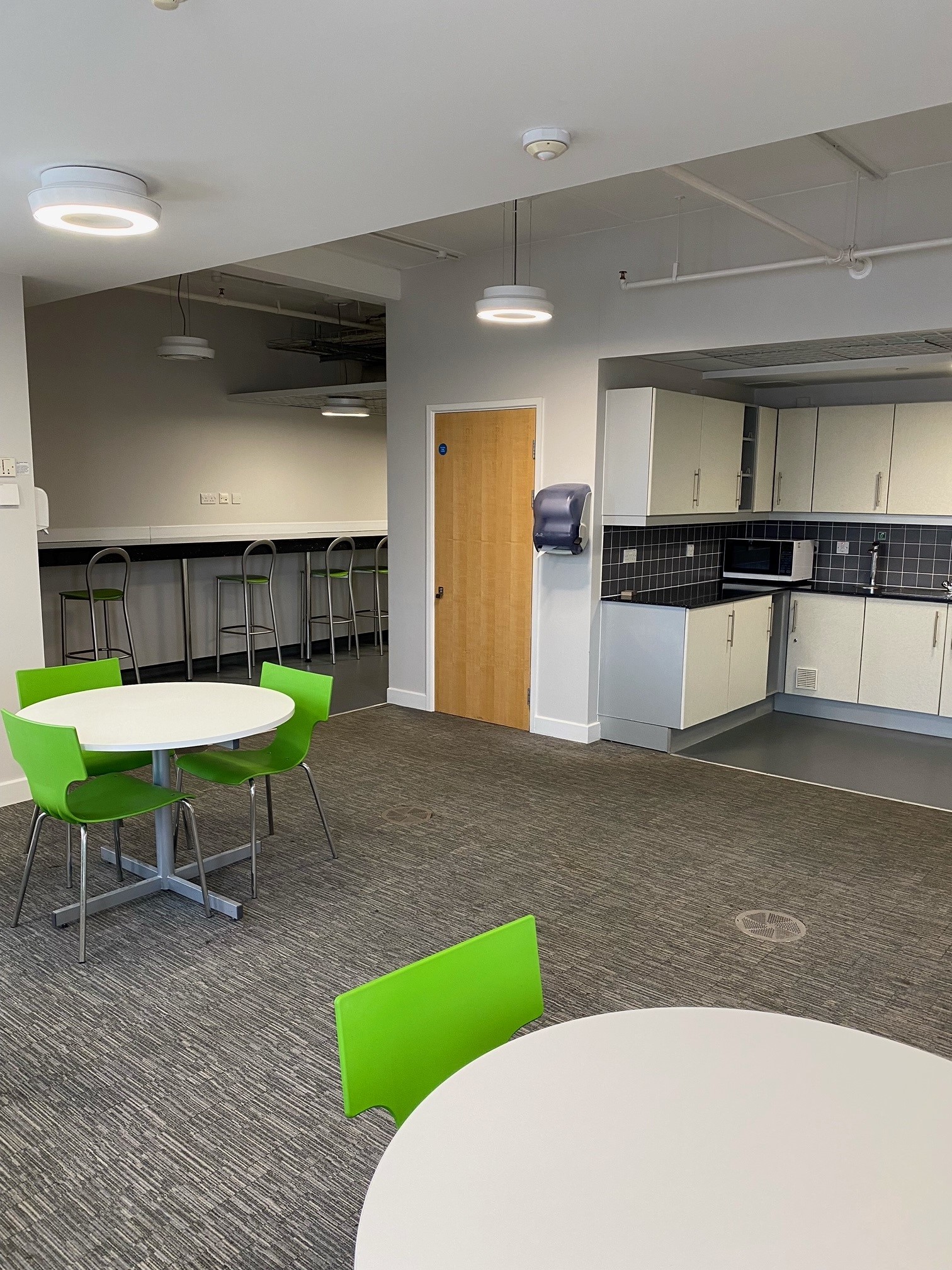 Interior of the Sandwell Start-Up Hub, with clean open space, round tables and a communal kitchen