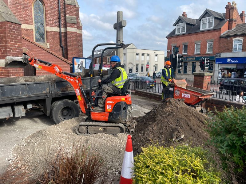 Red digger at work in the garden at St Mary's Church in Bearwood