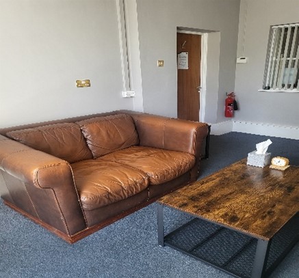 Bedford Lounge: a clean, light room with light brown leather sofa and modern coffee table with a box of tissues on it